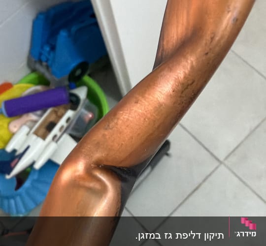 צינור נחושת מעוקם על רצפה עם כלים ברקע
